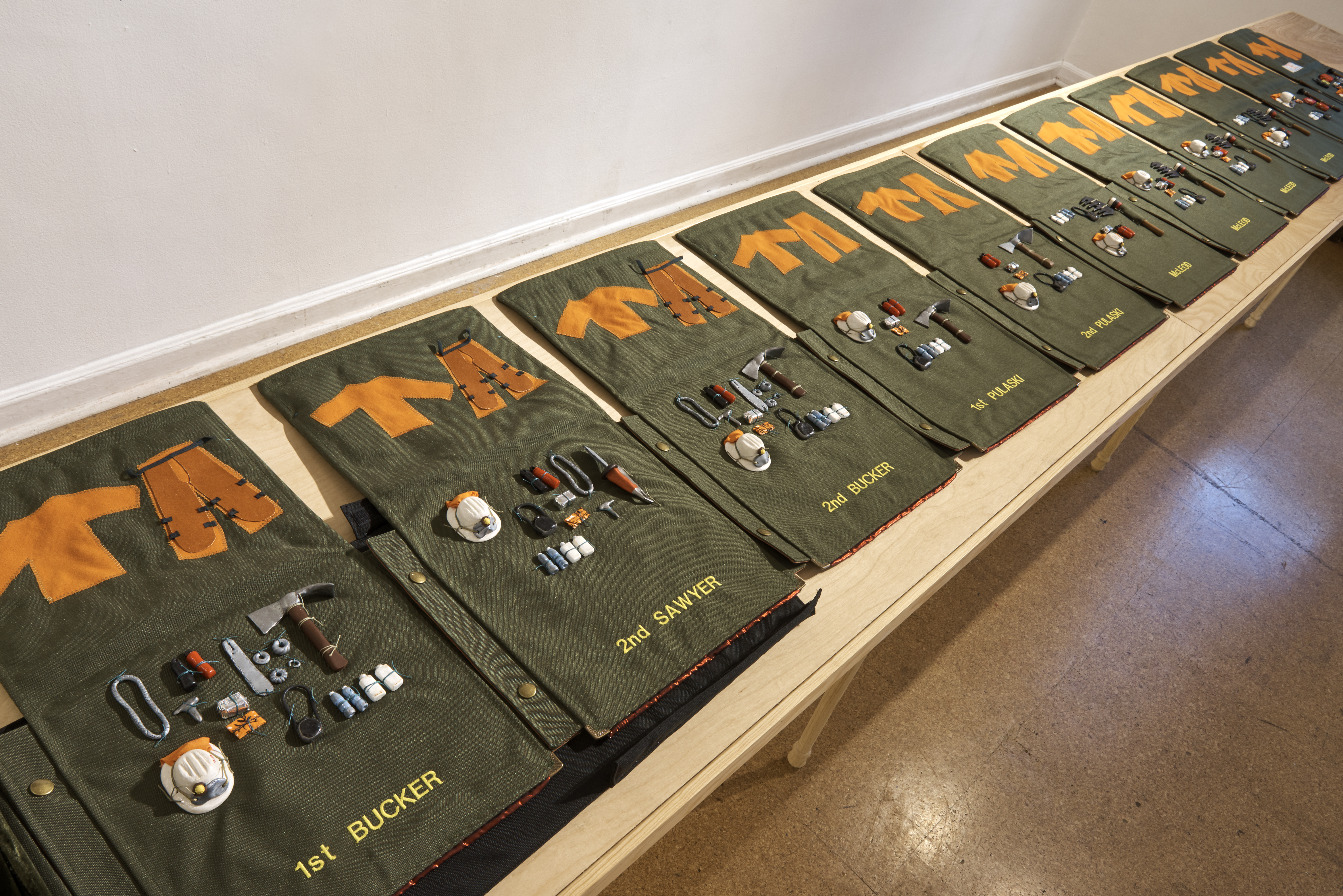 Kim Abeles and the Firefighting Women of Camp 13 / Valise 2 - Tools from the series, Valises for Camp Ground: Arts, Corrections, and Fire Management in the Santa Monica Mountains
2018
Hand constructed “backpack” valise made with Cordura, Velvet, Clay miniatures of firefighting tools, Embroidered names of each position on a fire crew, brass hardware 
Size: Closed: 23” x 10” x 14”   Open: 10” x 167” x 22"
This inaugural Camp Ground project with inmates from Camp 13 was managed by the Armory Center for the Arts, with Kim Abeles as the first commissioned artist. Camp Ground: Arts, Corrections, and Fire Management in the Santa Monica Mountains is made possible by the National Endowment for the Arts and the Los Angeles County Arts Commission.